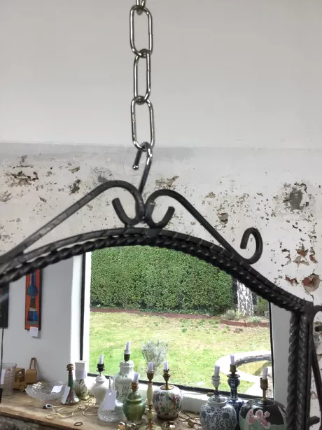 Wandspiegel mid-century met smeedijzeren ornamentering, gekartelde rand. Hardboard rugplaat. Weegt ruim 3 kg. Glas heeft slechts enkele zeer lichte slijtageplekjes.