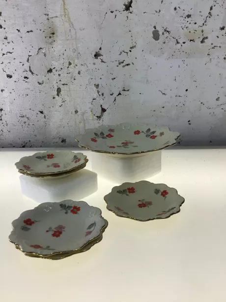 Vijf kleine schaaltjes en 1 klein bord met hetzelfde decoratief motief van een rode bloem met grijs blad. Gemaakt tussen 1913 en 1954.