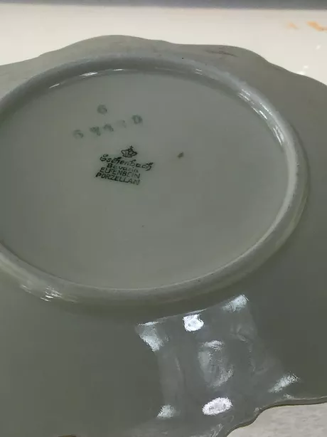 Vijf kleine schaaltjes en 1 klein bord met hetzelfde decoratief motief van een rode bloem met grijs blad. Gemaakt tussen 1913 en 1954.