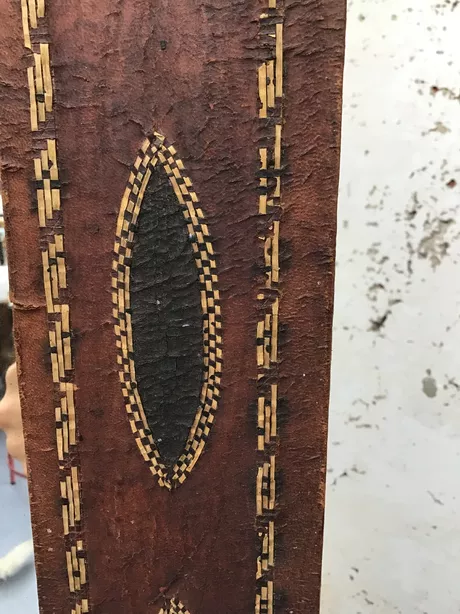 Antieke wandspiegel uit de jaren '20 of '30 van leer met de hand gemaakt met geometrische vormen leer getrokken over houten frame, koren, riet, van natuurlijke materialen gemaakt. Craquelé is zichtbaar en geeft dit stuk een ware antieke look. Het glas is oorspronkelijk en vertoont kleine weerplekken. Houten massief paneel op de rugzijde en authentiek ophangsysteem.