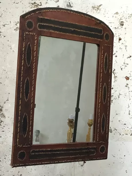 Antieke wandspiegel uit de jaren '20 of '30 van leer met de hand gemaakt met geometrische vormen leer getrokken over houten frame, koren, riet, van natuurlijke materialen gemaakt. Craquelé is zichtbaar en geeft dit stuk een ware antieke look. Het glas is oorspronkelijk en vertoont kleine weerplekken. Houten massief paneel op de rugzijde en authentiek ophangsysteem.
