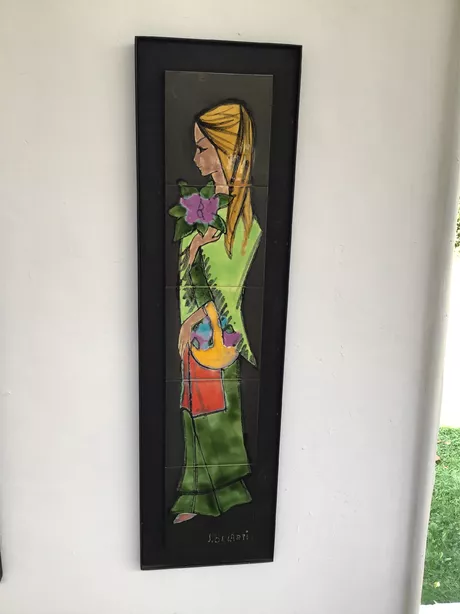 J. Belarti Paneel Vijf Tegels Vrouw met Bloem Dit paneel van het Belgische Atelier J. Belarti bestaat uit vijf keramische tegels die samen een kleurrijk vrouwelijk figuur met mand en bloem voorstellen op een zwarte achtergrond.