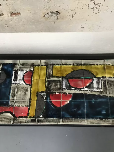 Deze unieke salontafel van J. Belarti dateert uit de zestiger jaren en bestrijkt 21 grote keramische tegels die samen een kleurrijke abstractie vormen. Een van de tegels is gesigneerd: J. Belarti. De vier poten zijn voorzien van rubberen beschermnoppen. Dit kunstwerk is puntgaaf en onbeschadigd.