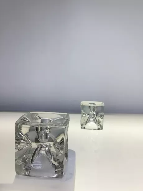 De SKLO Kubus-kandelaars zijn elegante, kubusvormige stijlvolle glazen kandelaars uit Tsjechië, ontworpen in de jaren ’60–’70 (vaak door Rudolf Jurnikl), uitgevoerd in massief geperst glas met een modernistisch reliëf, die de technische en esthetische kwaliteiten van SKLO Union laten zien. Geschikt voor een kaars en voor ene theelichtje. Op twee manieren te gebruiken.