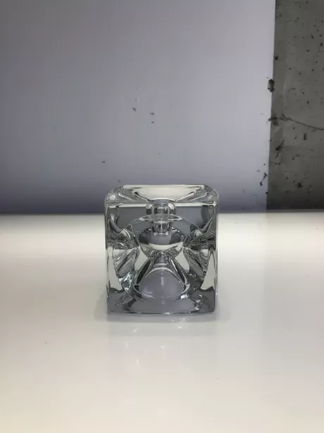 De SKLO Kubus-kandelaar is een elegante, kubusvormige stijlvolle glazen kandelaar uit Tsjechië, ontworpen in de jaren ’60–’70 (vaak door Rudolf Jurnikl), uitgevoerd in massief geperst glas met een modernistisch reliëf, die de technische en esthetische kwaliteiten van SKLO Union laten zien. Geschikt voor een kaars en voor ene theelichtje. Op twee manieren te gebruiken.