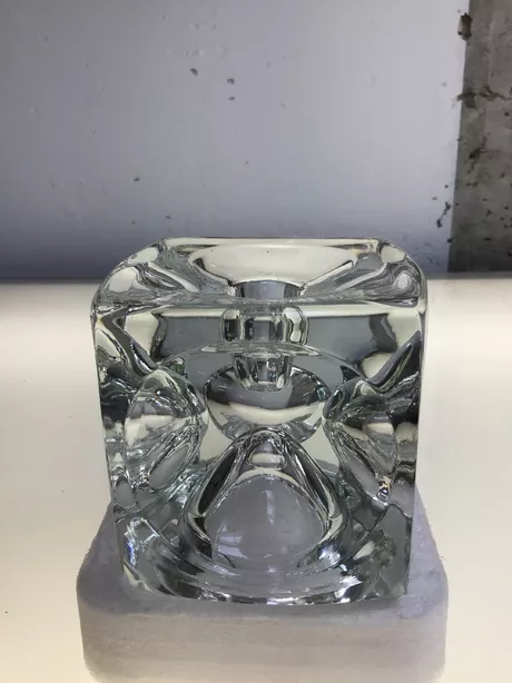 De SKLO Kubus-kandelaar is een elegante, kubusvormige stijlvolle glazen kandelaar uit Tsjechië, ontworpen in de jaren ’60–’70 (vaak door Rudolf Jurnikl), uitgevoerd in massief geperst glas met een modernistisch reliëf, die de technische en esthetische kwaliteiten van SKLO Union laten zien. Geschikt voor een kaars en voor ene theelichtje. Op twee manieren te gebruiken.