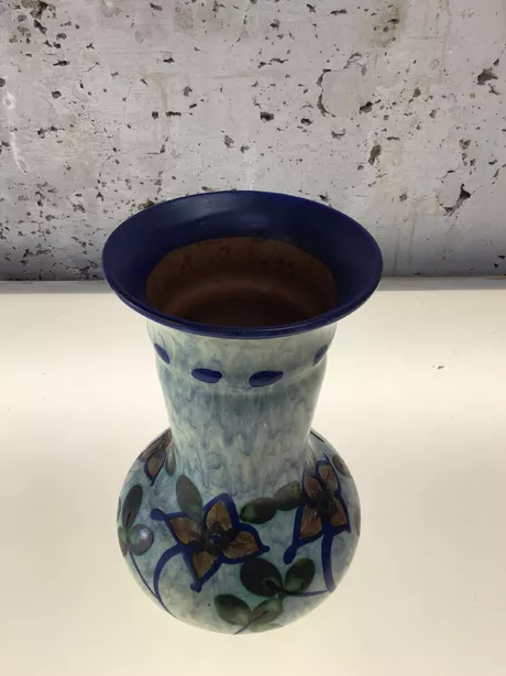 Deze zeldzame vaas werd gemaakt in Zweden in de jaren '50. Donkerblauwe pasteuze rand. Handgeschilderd voorzien van bloem- en bladmotief op een lichtblauwe achtergrond. "UE" gesigneerd aan de onderzijde. Deze vaas is onbeschadigd en puntgaaf.