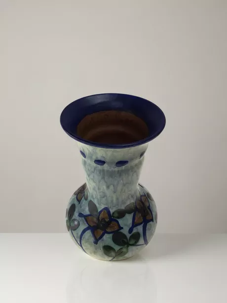 Deze zeldzame vaas werd gemaakt in Zweden in de jaren '50. Donkerblauwe pasteuze rand. Handgeschilderd voorzien van bloem- en bladmotief op een lichtblauwe achtergrond. "UE" gesigneerd aan de onderzijde. Deze vaas is onbeschadigd en puntgaaf.